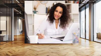 Portrait of positive female employee engaged in business activities at workplace in office Wall mural