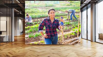 Portrait of positive hispanic woman gardener posing in vegetable garden on sunny fall day Wall mural