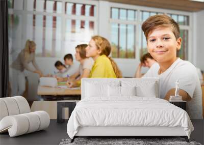 Portrait of positive schoolboy posing in classroom during lesson in secondary school Wall mural