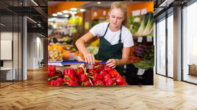 Portrait of teenage girl working in supermarket as job experience, selling red pepper Wall mural