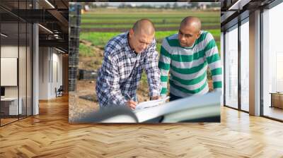 Portrait of two skilled male gardeners discussing contract and signing papers outside Wall mural