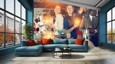 Portrait of two young women drinking cocktails and talking on corporate party Wall mural