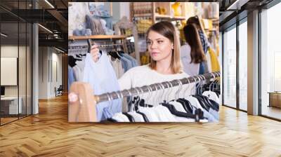 Portrait of woman customer looking blue shirt in the fashion store Wall mural