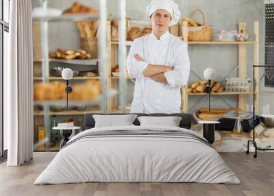 Portrait of young man baker smiling at camera posing during daily work in small bakery Wall mural