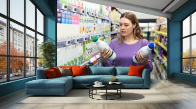 Portrait of young smiling woman customer choosing milk and dairy products in grocery Wall mural