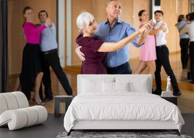 Positive active elderly couple enjoying slow foxtrot in dance studio. Amateur social dancing concept Wall mural