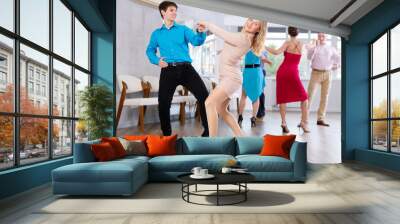 Positive adult pairs practicing vigorous jive movements in dance class Wall mural