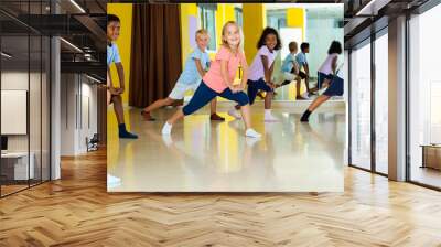 Preteen boys and girls practicing dance, stretching with female trainer in dance hall. Wall mural