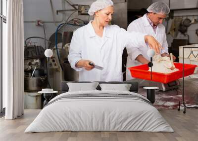 Professional female baker with male assistant portioning dough with scraper and weighing pieces Wall mural