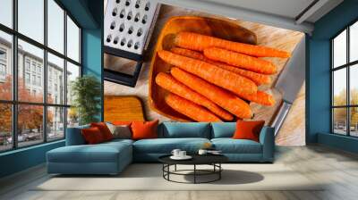 Raw carrots and kitchen supplies on wooden background, food preparation Wall mural