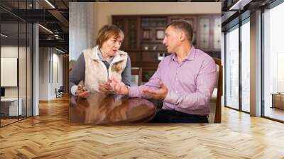 Senior woman having conversation with her adult son at living room Wall mural