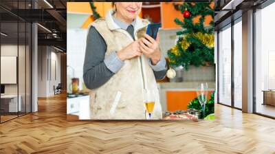 Senior woman using phone during cooking christmas dinner at home Wall mural