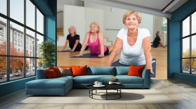 Senior women practicing cobra pose during group yoga training. Wall mural