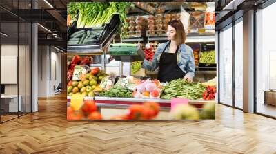 shopping assistant weighing fruit and vegetables in grocery shop Wall mural