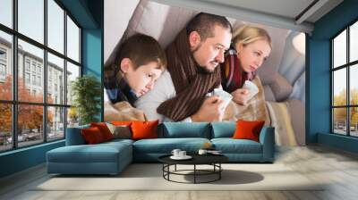 Sick parents and son under blanket Wall mural