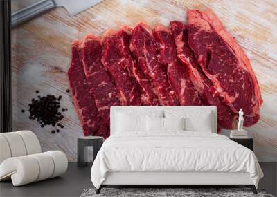 Sliced raw marbled veal steaks with peppercorns ready to cook on wooden table Wall mural