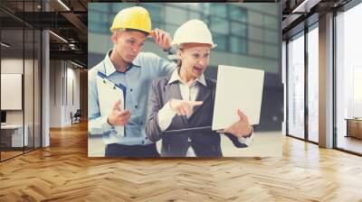 Smiling engineer with woman designer are exploring project in laptop Wall mural