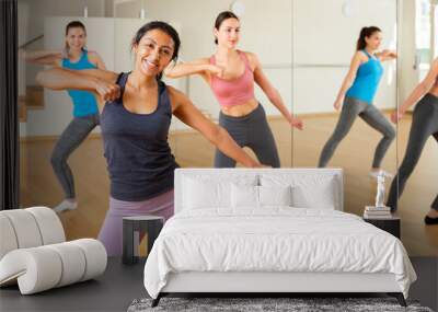 Smiling females wearing sport clothes dancing together in light dance studio Wall mural