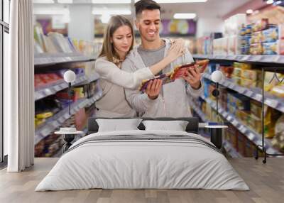 Smiling woman and man buying chocolate Wall mural