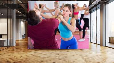 Sporty female with trainer are doing self-defence moves in gym Wall mural