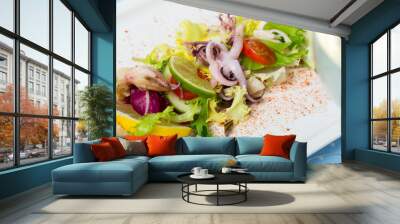 Tasty salad of boiled squids, lemon and lettuce leaves at plate Wall mural