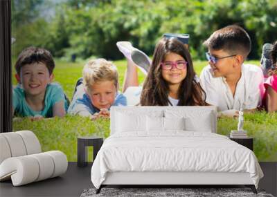 Team of friends children resting on grass together in park Wall mural