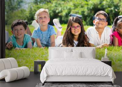 Team of friends children resting on grass together in park Wall mural