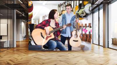 Teenage choosing best acoustic guitar Wall mural