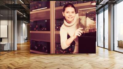 Teenage girl shows an aquarium with fish fry Wall mural