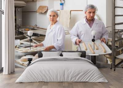 Two focused bakers working in bakery, preparing shaped raw dough for proofing before baking Wall mural