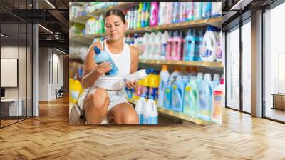 Woman carefully selects cleaning product in industrial section of a supermarket Wall mural