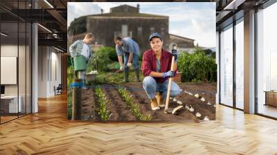 woman farmer with a garden tool near growing seeds. Planting seeds and fertilizing the land on the farm. A farmer and his family grow organic berries and vegetables Wall mural