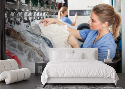 worker of laundry inspecting clothes after dry cleaning Wall mural