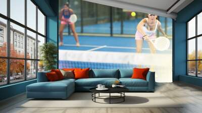 Young and adult women in doubles play tennis on tennis court Wall mural