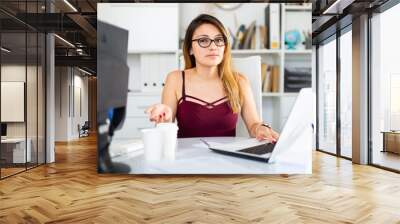 Young colombian woman in glasses working with laptop at the office table Wall mural