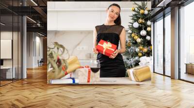 young girl stands in kitchen. she smiles and holds New Year s gift in her hands Wall mural