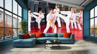 Young girls and boys in kimono and belts sparring during karate training. Wall mural