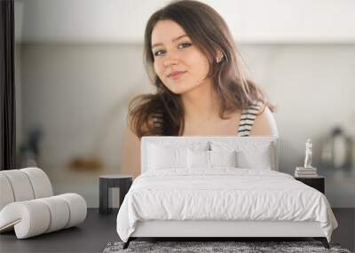 Young smiling woman posing standing in kitchen at home Wall mural