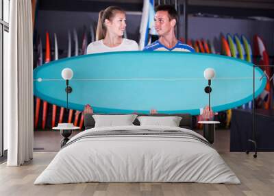 Young spanish couple is posing in surfboard store on the beach.. Wall mural