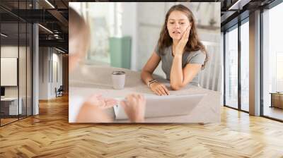 Young woman agent communicating kindly with female business-partner sitting at the kitchen-table Wall mural