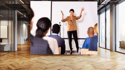 Young woman motivational coach giving lecture at business convention at conference hall Wall mural