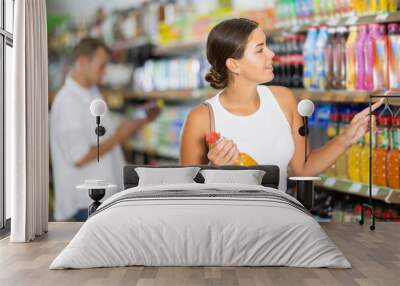 Young woman shopper choosing soda in grocery store Wall mural