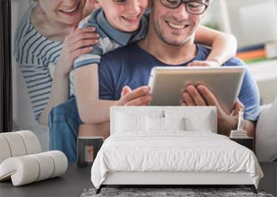 a cheerful family has fun together by playing on a tablet Wall mural