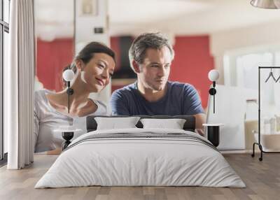 A couple using a laptop while having breakfast in the kitchen Wall mural