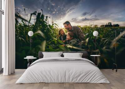 A farmer and his two children in a cornfield at sunset, with farm equipment in the background. Generative ai Wall mural