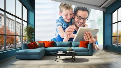 a father and his young son having fun by  playing on a tablet Wall mural