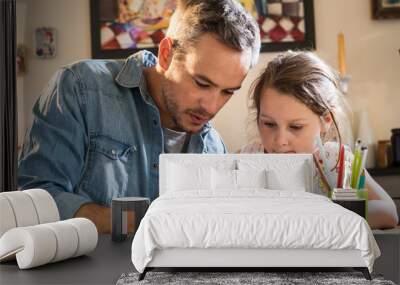 A father helps his little daughter to do her homework for the school. Wall mural