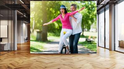 A lovely couple is having fun on a unicycle in the park. Wall mural