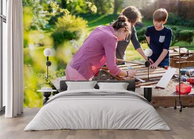 A mother and her two children build wooden planters for their permaculture vegetable garden Wall mural