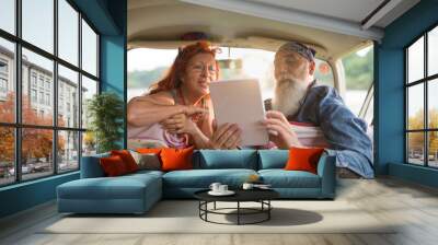 An old hipster couple sitting in a van, using a digital tablet Wall mural